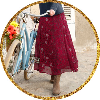 Woman wearing a flowy floral print maxi skirt in wine red.